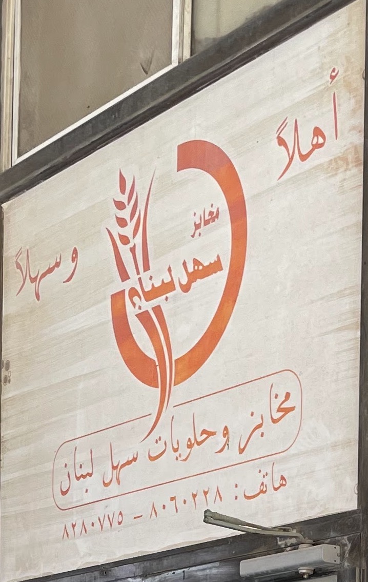 لوحة مخابز وحلويات سهل لبنان فوق باب المحل، بالشعار البرتقالي وأرقام الهاتف